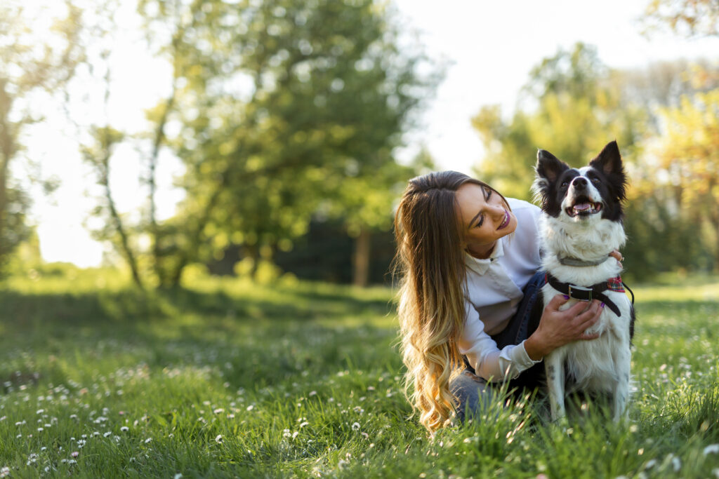 Woman with playful dog on fresh green meadow